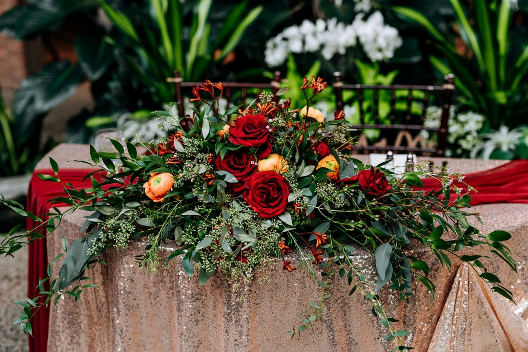 Sweetheart table decor with sequin tablecloth and floral piece.