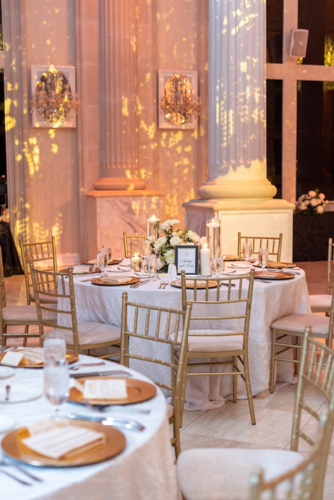 Ballroom reception with white guest table settings.