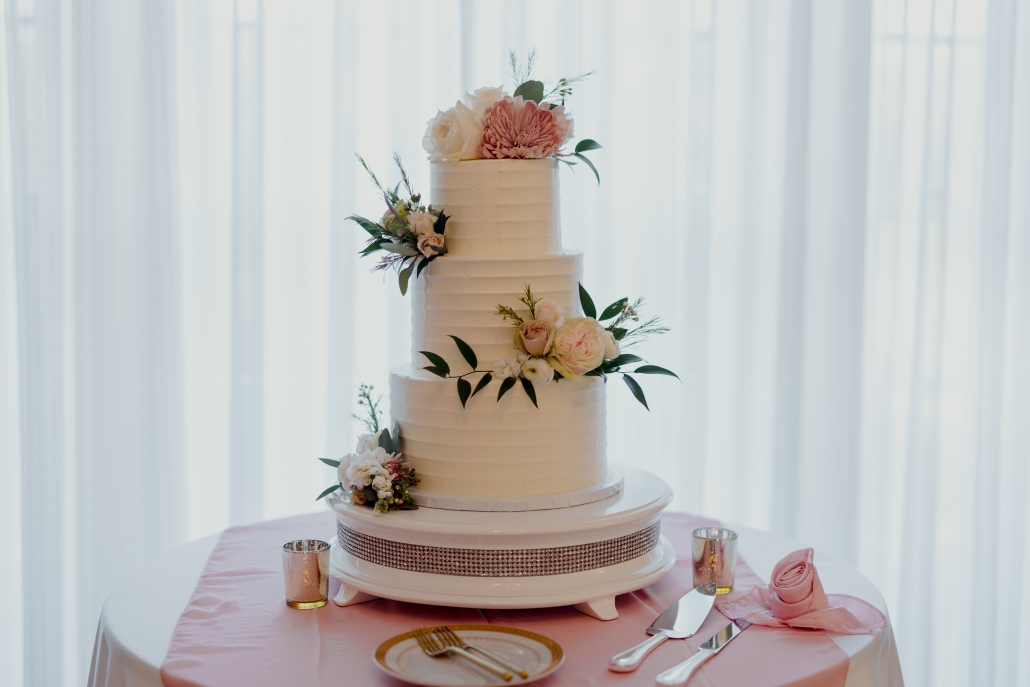 Classic 3 tiered white wedding cake with pink floral accents